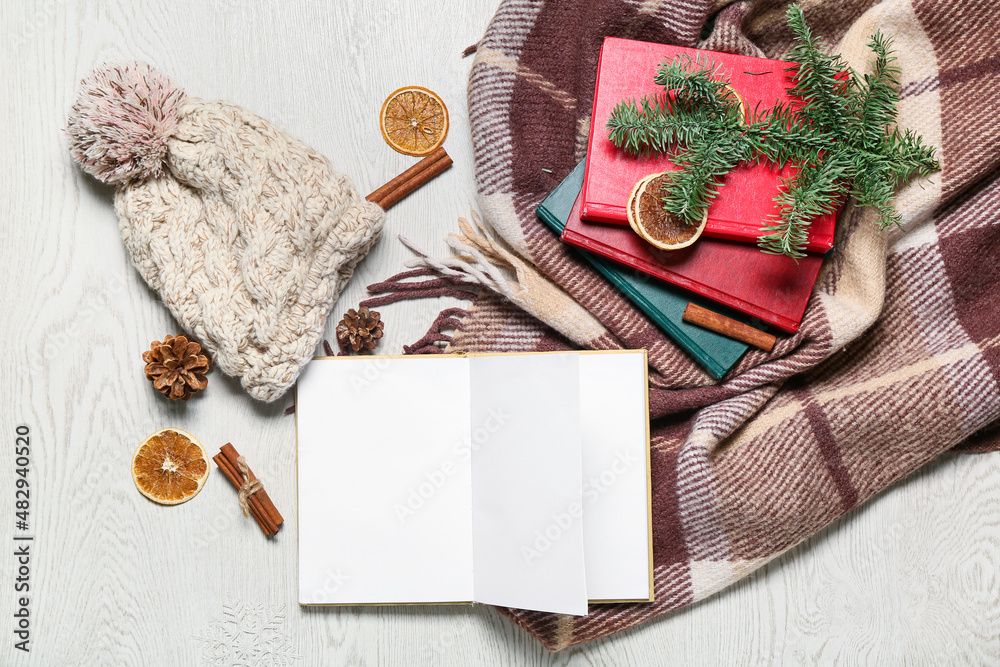 Books, winter clothes, plaid and fir tree branch on light wooden background Books, winter clothes, plaid and fir tree branch on light wooden background