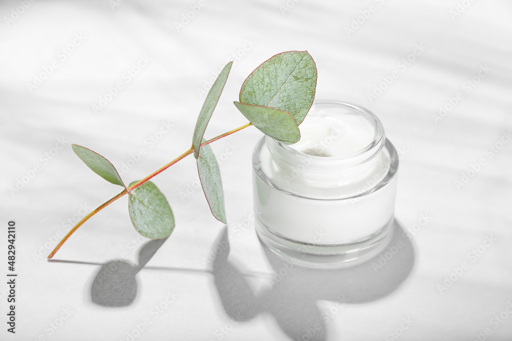 Jar with natural cosmetic cream and eucalyptus branch on white background Jar with natural cosmetic cream and eucalyptus branch on white background
