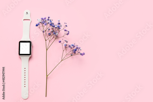 Modern smartwatch and flower on color background