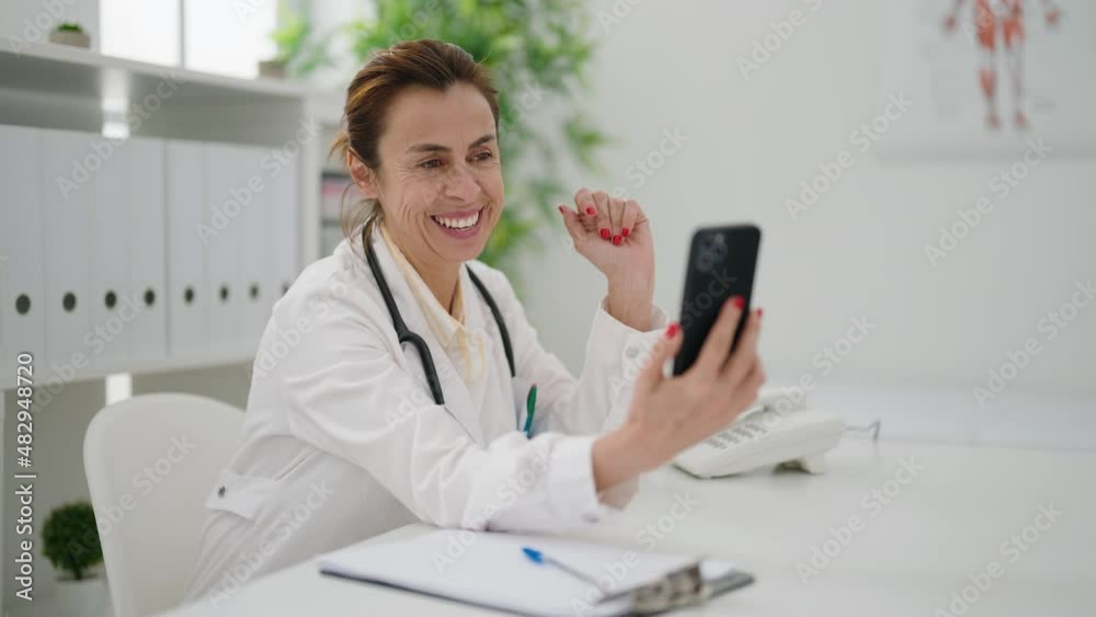Middle age woman wearing doctor uniform having teleconsultation at clinic Middle age woman wearing doctor uniform having teleconsultation at clinic