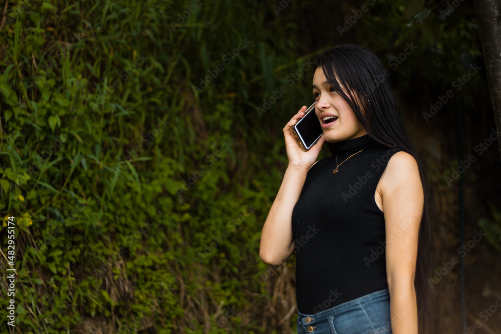 Una foto de una chica caucásica usando un smartphone durante la publicidad en un parque Una foto de una chica caucásica usando un smartphone durante la publicidad en un parque