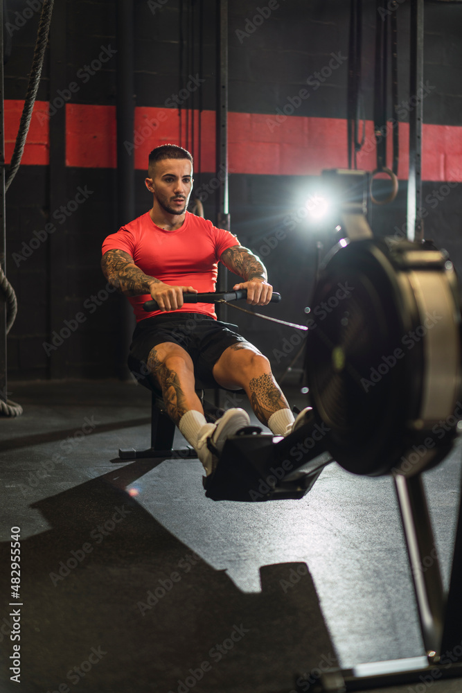 Chico musculoso con camiseta roja practicando deporte en un gym