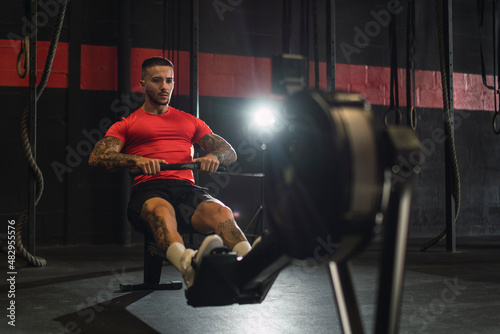 Chico musculoso con camiseta roja practicando deporte en un gym