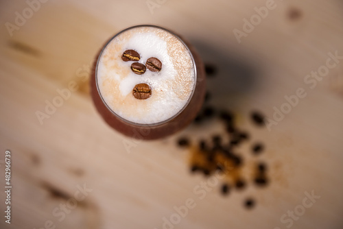 Crushed ice coffee with cinamon in brandy glass from above on table with wood background and coffee beans