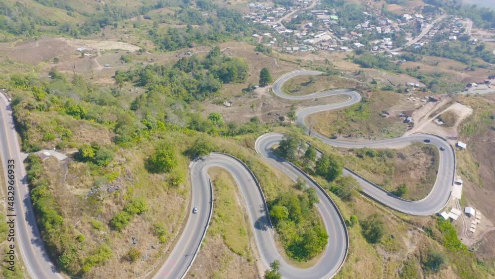 Aerial view of cars driving on curved, zigzag curve road or street on mountain hill with green natural forest trees in rural area of Nan, Thailand. Transportation.