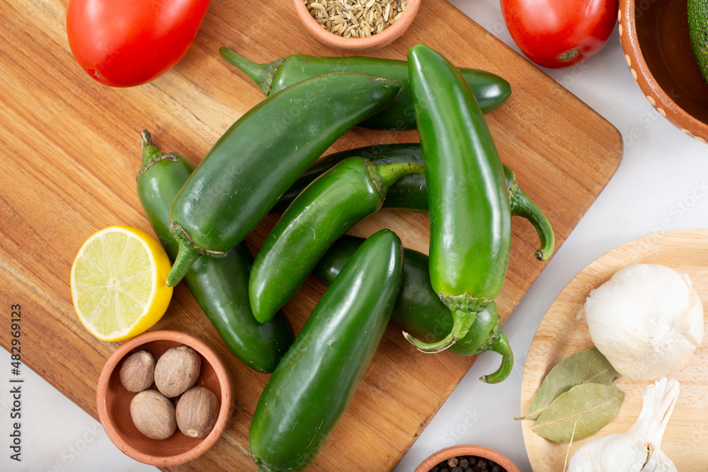A top down view of several jalapeño chiles, among other salsa ingredients. A top down view of several jalapeño chiles, among other salsa ingredients.