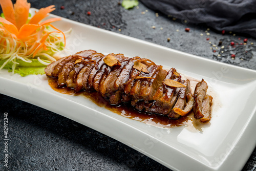 Peking duck on plate on dark stone table, Chinese cuisine