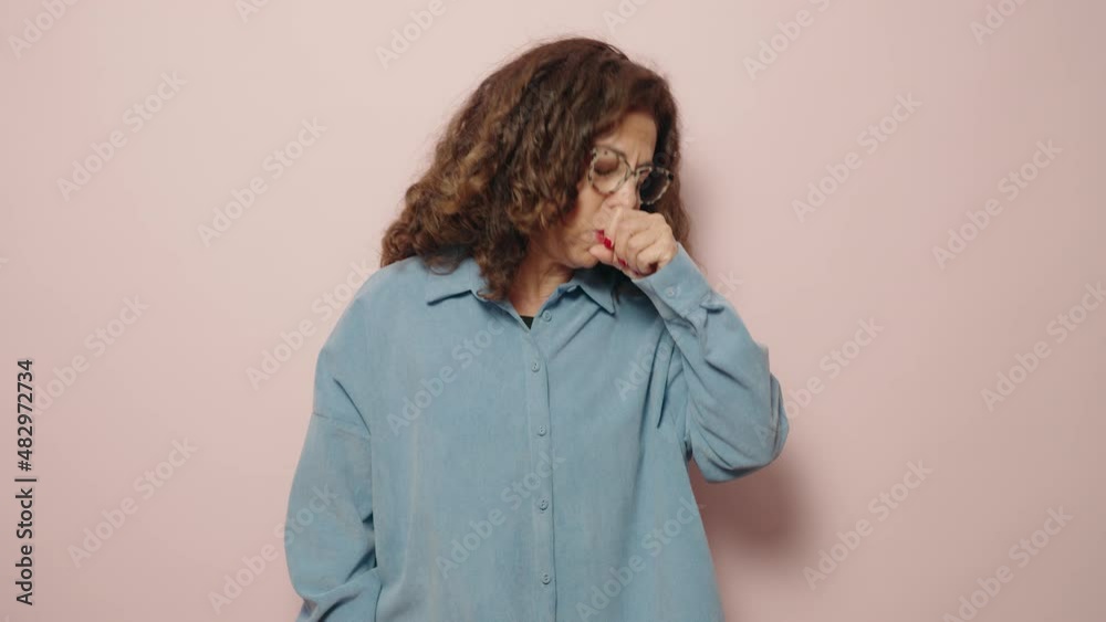 Middle age woman coughing over pink background Middle age woman coughing over pink background