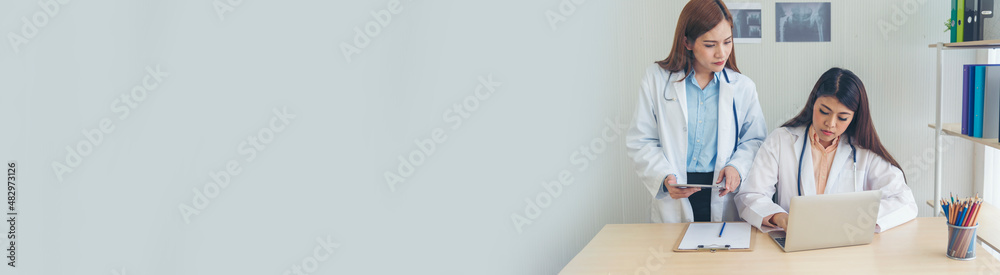 Banner two asian women doctor medical lab discussing together healthcare teamwork. Panorama Two asian women doctors meeting in medical clinic office using laptop discussion patient with copy space. Banner two asian women doctor medical lab discussing together healthcare teamwork. Panorama Two asian women doctors meeting in medical clinic office using laptop discussion patient with copy space.