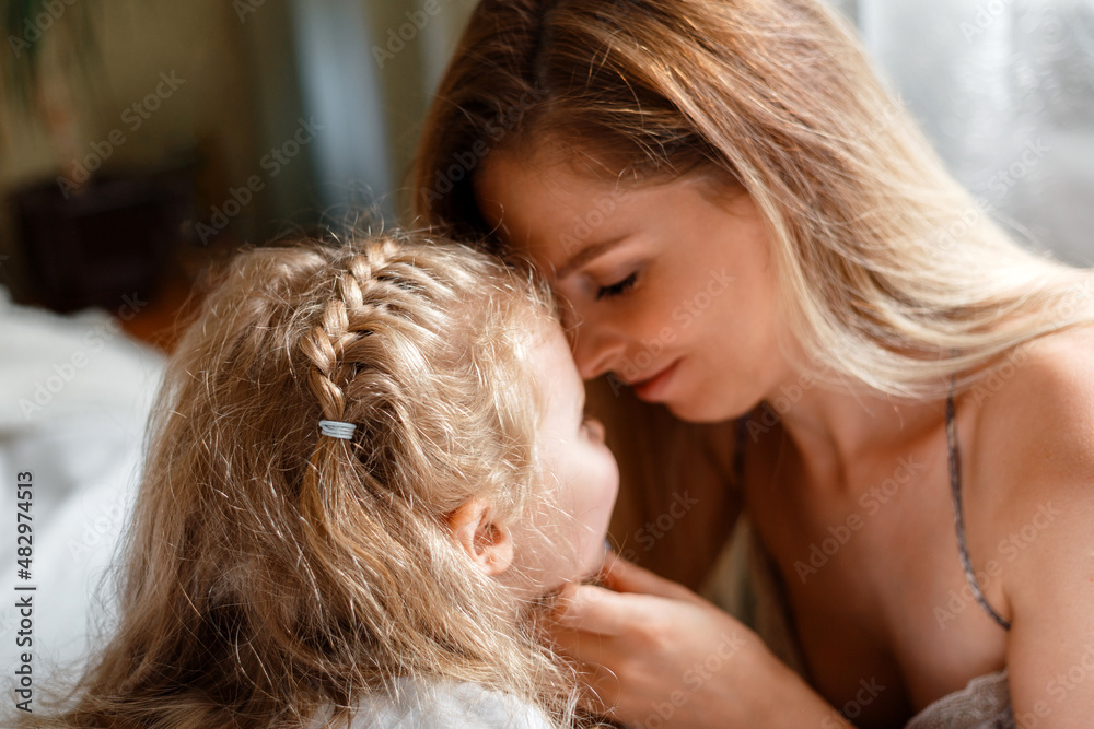 Portrait of blondes mother 30s and daughter 5 years. Beautiful mom gently touches child girl face at home. Loving caring mom show tenderness love to her kid. Mother's day in happy family. Portrait of blondes mother 30s and daughter 5 years. Beautiful mom gently touches child girl face at home. Loving caring mom show tenderness love to her kid. Mother's day in happy family.