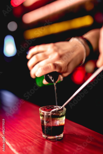 Shot preparation. Night club, bar. Close-up bartender's hand pouring alcohol