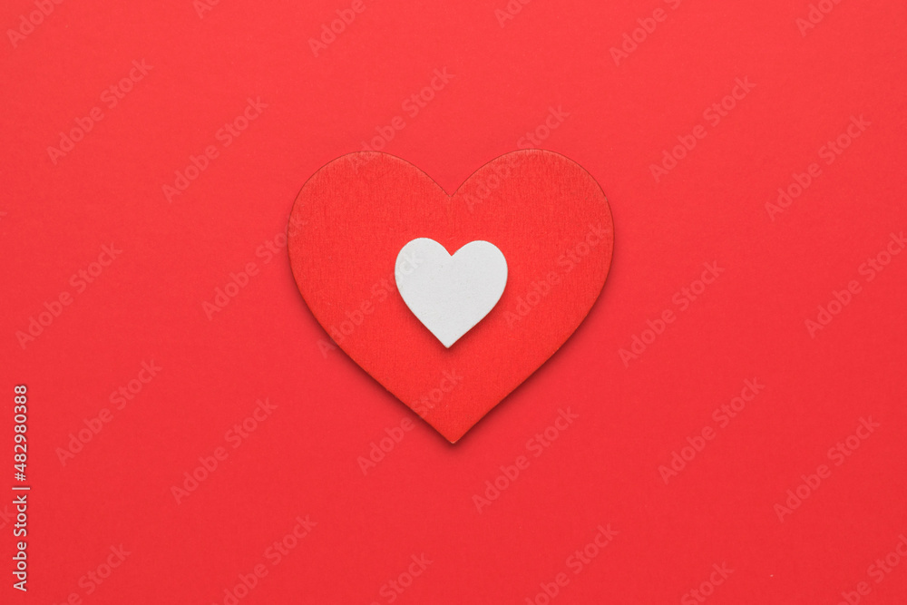 A big red and a small white heart on a red background. The concept of falling in love and Valentine's day. Minimalism. A big red and a small white heart on a red background. The concept of falling in love and Valentine's day. Minimalism.