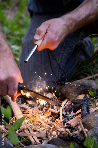 A close-up of a man lighting a fire with a ferro rod and a survival knife.