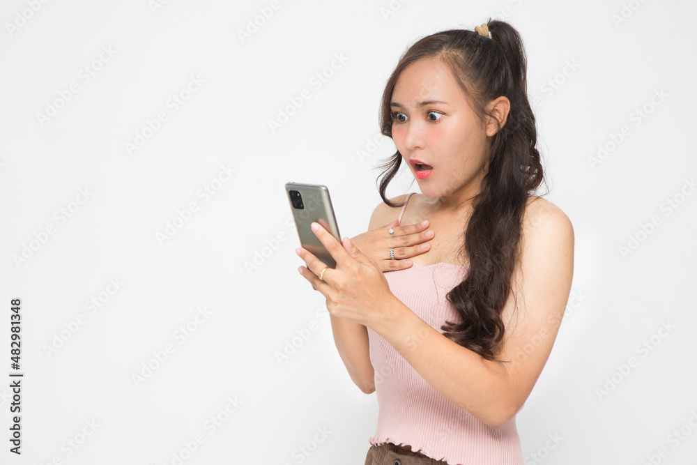 Cute Asian woman is shocked something on her smartphone for social media concept Cute Asian woman is shocked something on her smartphone for social media concept