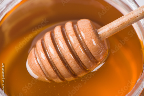 close up of honey with honey dipper in glass bowl