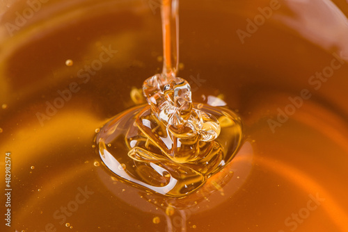 close up of honey dripping in glass bowl