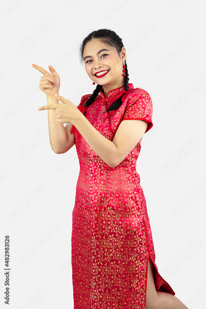 Asian girl in red cheongsam pointing something isolated on white background. Chinese new year concept style. Asian girl in red cheongsam pointing something isolated on white background. Chinese new year concept style.