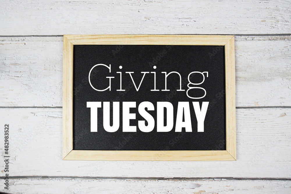 Giving Tuesday text on blackboard flat lay on wooden background Giving Tuesday text on blackboard flat lay on wooden background