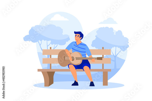 The young man sitting on the bench and playing acoustic guitar in the park.