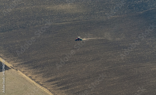 Aerial view of a tractor on a big agriculture field while plowing the land. Prepare for seed planting, plow the fields. Agriculture and farming industry.