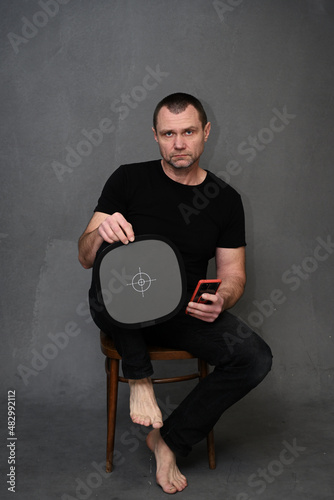 portrait of a man with a smartphone in his hand and a target looking at the camera