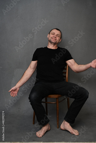 Adult man lounging on a chair on a gray background