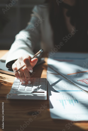 Close up Business woman using calculator for audit finance budget on wooden desk in office, tax, accounting, statistics and analytic research concept. photo