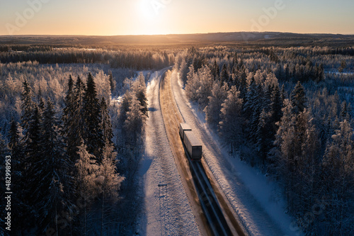Cargo truck on a highway in winter landscape against sunset. Delivery and transportation in northern europe.