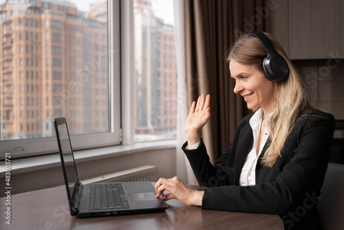 Distance education concept. A woman teacher or tutor has a lesson in zoom sitting at home at the workplace, a consultant in headphones advises