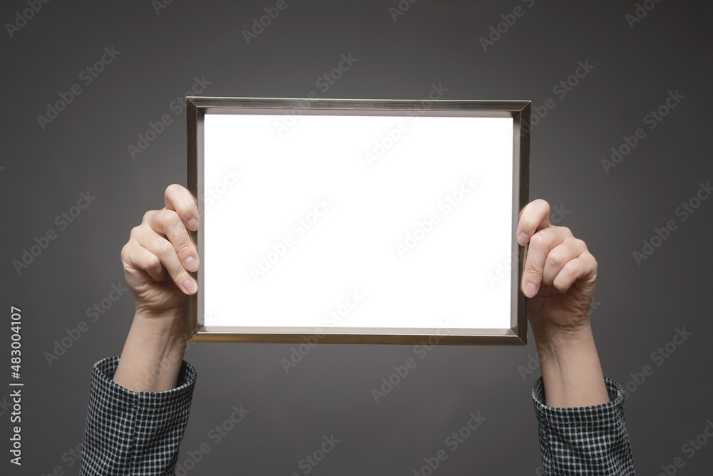 A blank diploma certificate mock up. An empty photo frame in female hands raised above her head close up. A blank diploma certificate mock up. An empty photo frame in female hands raised above her head close up.
