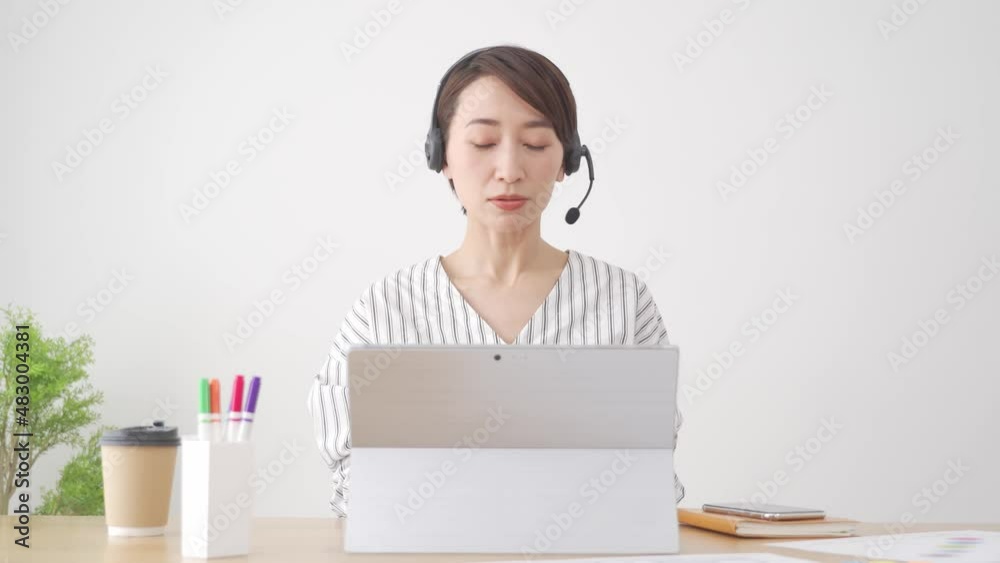 パソコンに向かって説明する日本人女性 パソコンに向かって説明する日本人女性