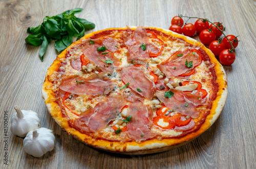 pizza with prosciutto crudo, mushrooms, mozarella, red bell peppers and parsley #483004396