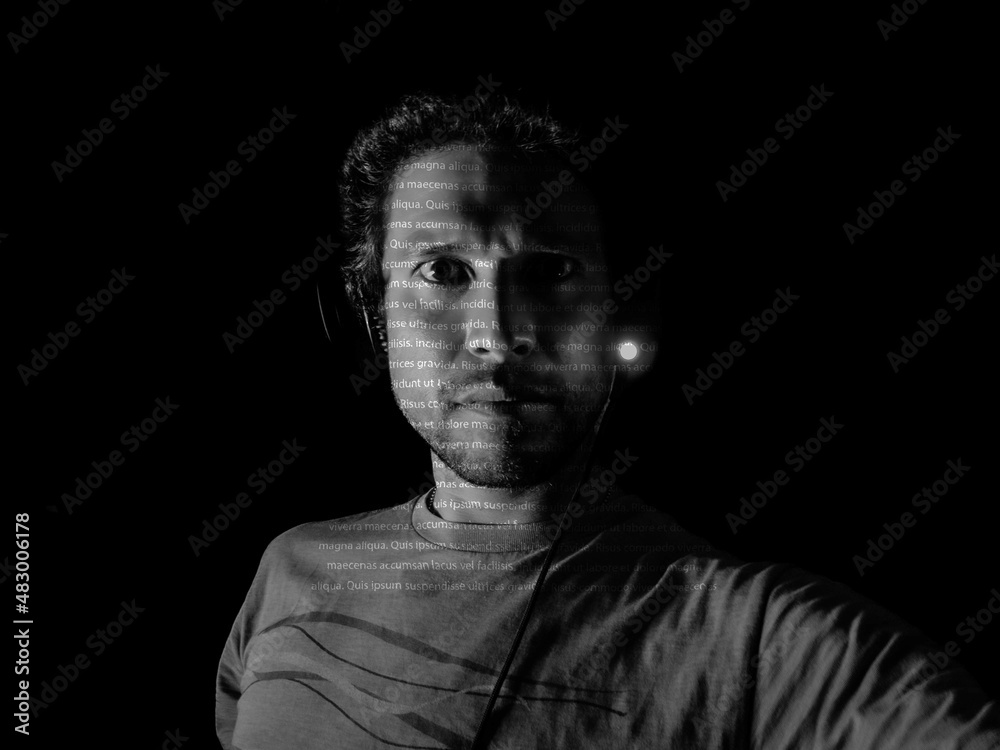 A man with letters projected on his face in a dark room A man with letters projected on his face in a dark room