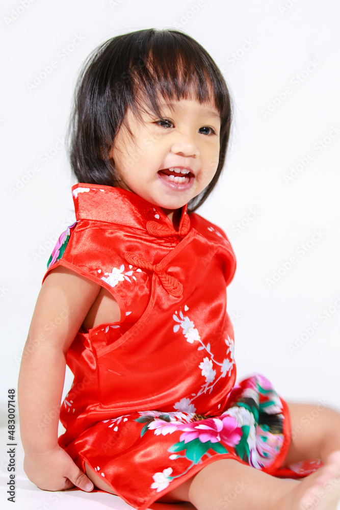 Studio shot of little cute innocent Asian kindergarten preschooler daughter girl kid model short black hair in red Chinese traditional qipao Cheongsam outfit sitting alone on white background. Studio shot of little cute innocent Asian kindergarten preschooler daughter girl kid model short black hair in red Chinese traditional qipao Cheongsam outfit sitting alone on white background.