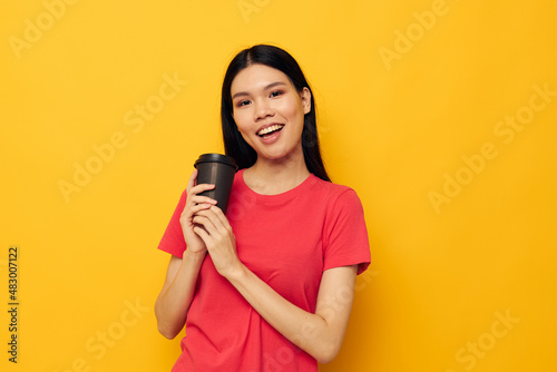 woman in a red t-shirt glass with a drink yellow background