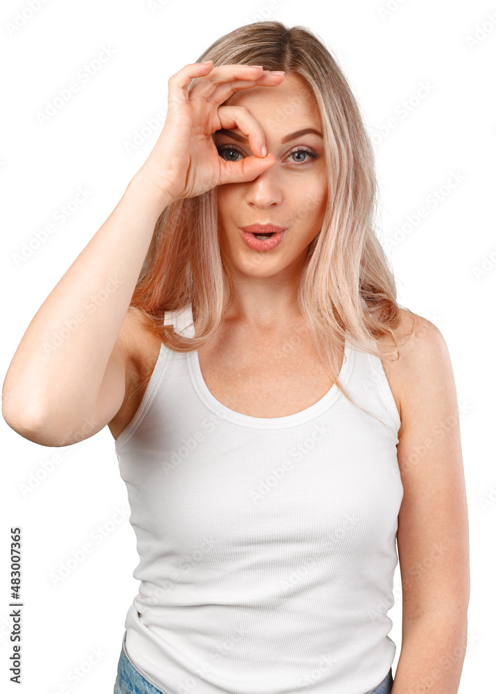 Joyful blonde caucasian female looking at camera through fingers in okay gesture isolated on white