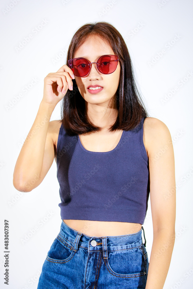Portrait isolated closeup studio cutout shot of Asian female model in crop top shirt jeans and sunglasses smiling look at camera on white background Portrait isolated closeup studio cutout shot of Asian female model in crop top shirt jeans and sunglasses smiling look at camera on white background