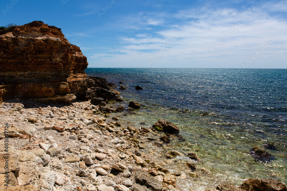 View of the cliff, an empty beach of stones and the sea