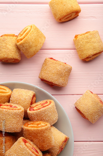Homemade cookies, mini rolls with apricot jam in plate on pink background. Top view