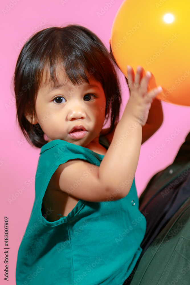 Portrait studio shot little cute Asian kindergarten preschooler girl daughter model in casual long dress holding colorful balloons on pink background Portrait studio shot little cute Asian kindergarten preschooler girl daughter model in casual long dress holding colorful balloons on pink background