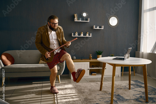 Funny freelance businessman playing broom like guitar