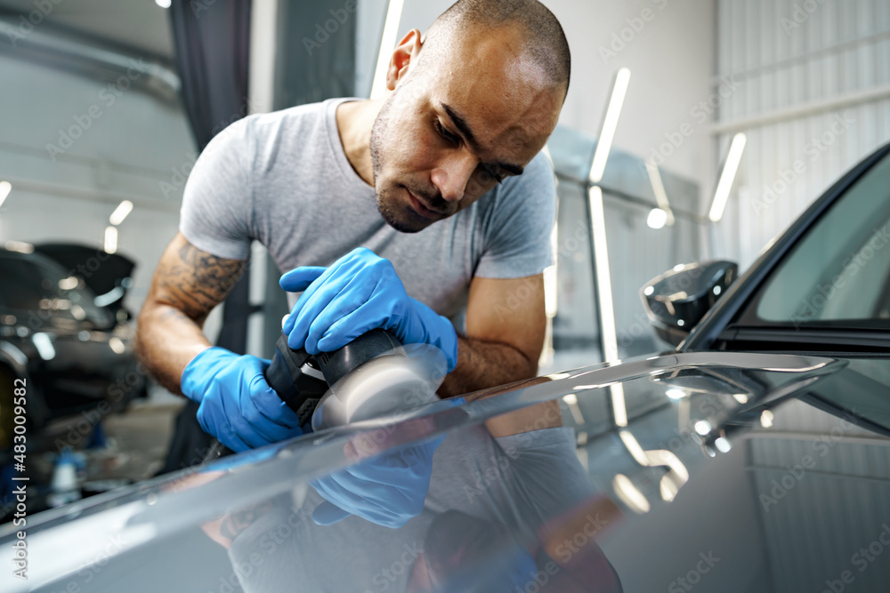 Car detailing. Male hands with orbital polisher in auto repair shop Car detailing. Male hands with orbital polisher in auto repair shop