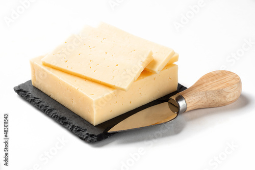 Russian cheese slicing on a white background for insulation. Classic cheese on a stone board with a slicing knife