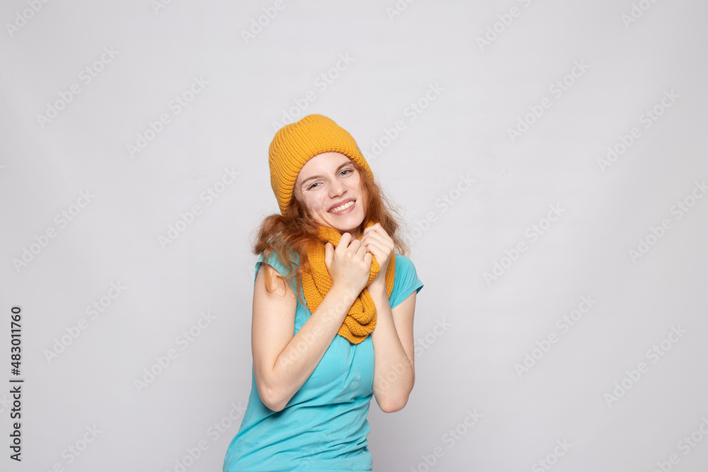 red-haired girl in a warm hat on a light background red-haired girl in a warm hat on a light background
