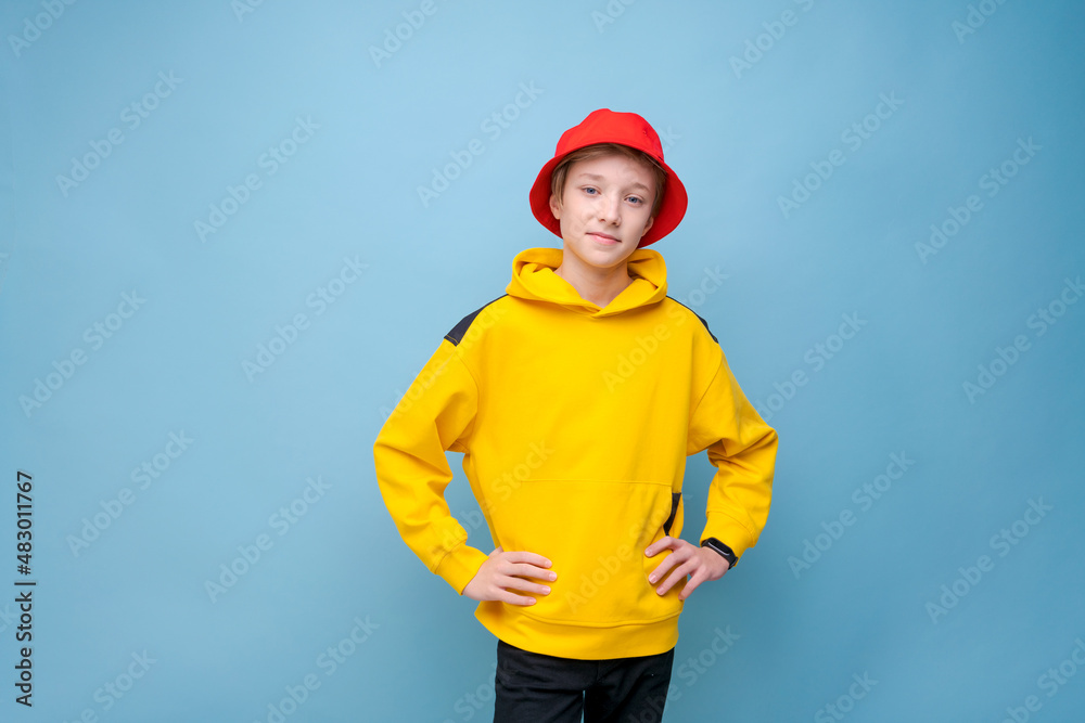 Portrait of positive guy in yellow jacket and a red panama hat on a blue background, looking at the camera with a smile on his face. Happy caucasian teenager posing in cute smiling studio Portrait of positive guy in yellow jacket and a red panama hat on a blue background, looking at the camera with a smile on his face. Happy caucasian teenager posing in cute smiling studio