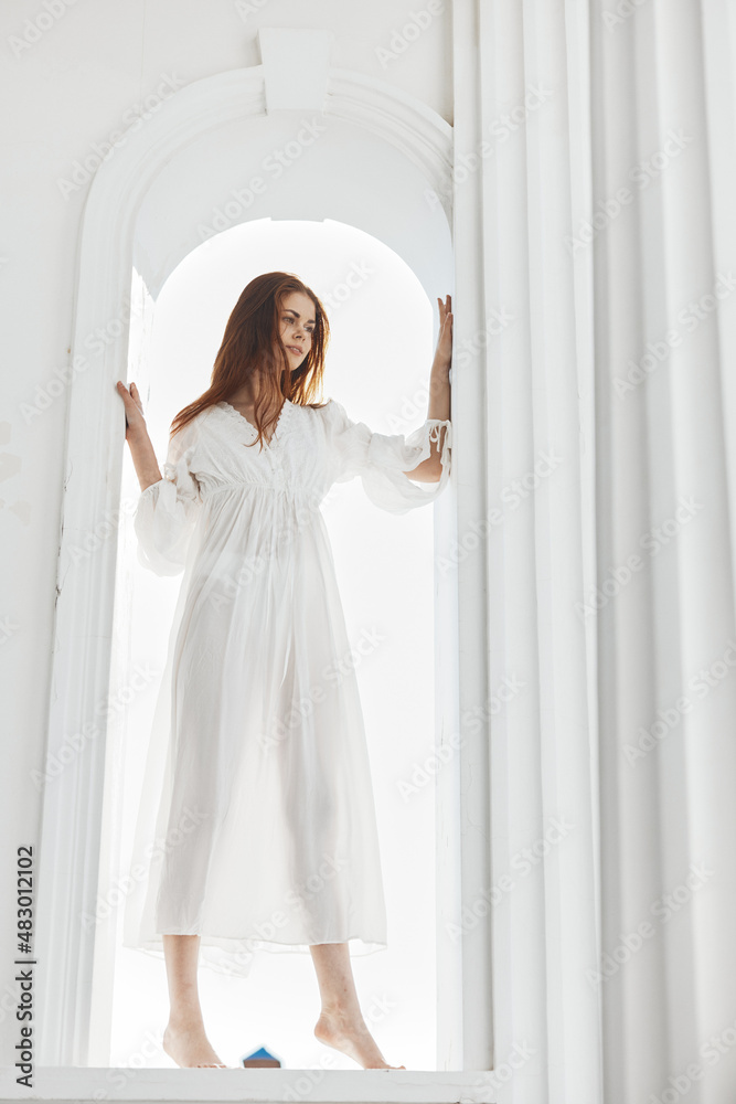beautiful woman in white dress barefoot in the window opening beautiful woman in white dress barefoot in the window opening