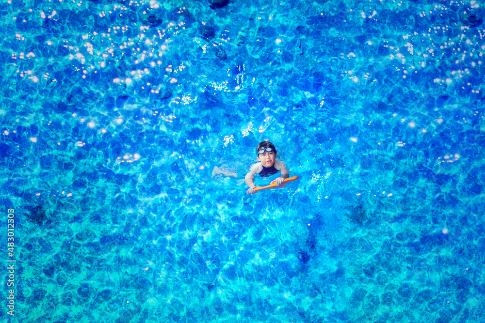 Top down view of happy little boy swimming on pool