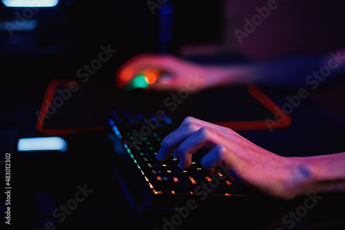 Gamer play computer game, use rgb neon colored keyboard