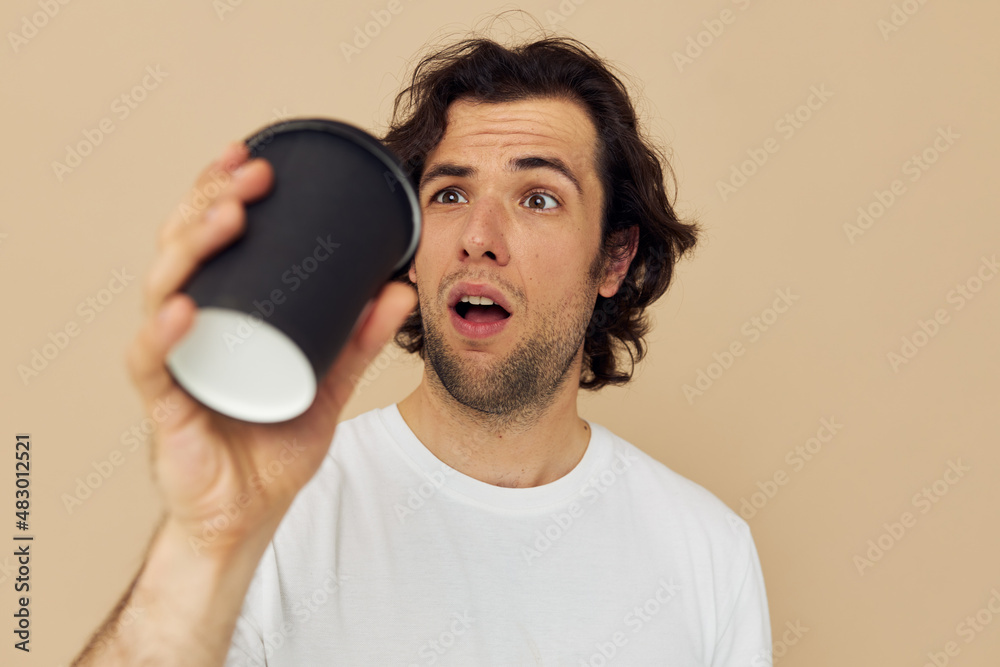 handsome man in a white T-shirt with a black glass in hand Lifestyle unaltered handsome man in a white T-shirt with a black glass in hand Lifestyle unaltered