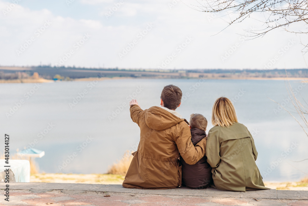 Fototapeta premium young beautiful family sitting at beach with view lake
